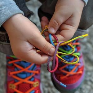 niño atandose los coloridos cordones de sus zapatillas