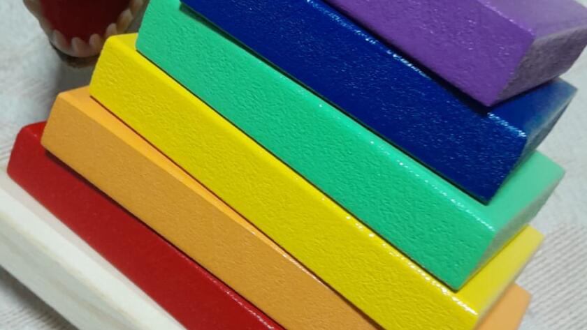 Torre de bloques de madera coloridos con dinosaurio de fondo