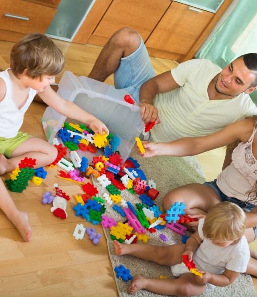 Ordinary happy family of four relaxing at home with toys